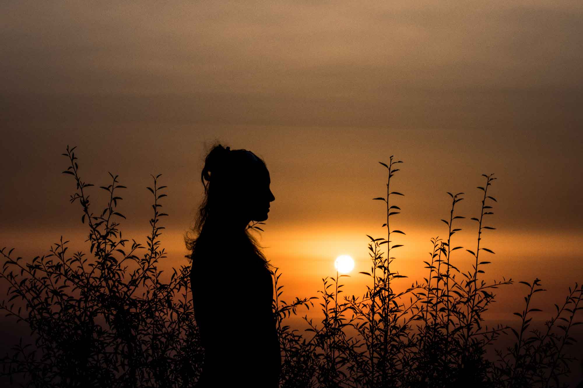 Kvinne står i solnedgang